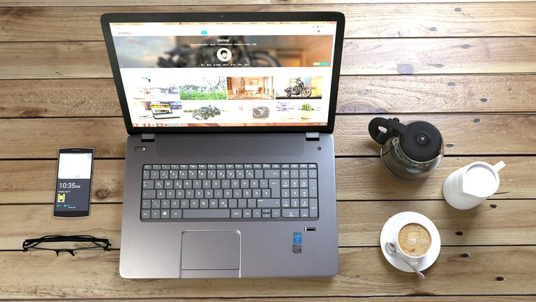 Ordinateur, tasse de café, lunettes et GSM disposés pour commencer à travailler